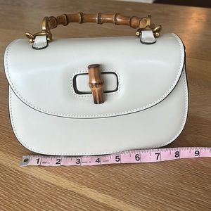 Small leather bag with bamboo handle, two removal straps. Off-white/bone color.